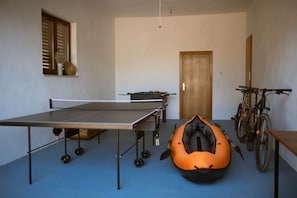 Une pièce équipée d’une table de ping-pong, d’un baby-foot, d’un kayak et d’un vélo.