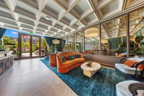 A spacious lobby with a high ceiling, a blue carpet, and a seating area with a sofa and chairs. - Cozy 1BR- Pool -Steps to Wynwood Walls (Miami)