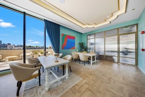 A modern interior with a dining area, large windows, and a city view. - Cozy 1BR- Pool -Steps to Wynwood Walls (Miami)
