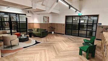 Un intérieur moderne avec un parquet en chevrons, un canapé vert, une table basse ronde et un pouf rouge.