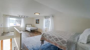 A bedroom with a bed, a window, a chair, and a staircase.