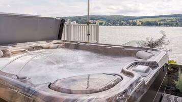 Een hottub met uitzicht op een meer en heuvels op de achtergrond.