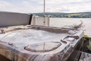 A hot tub with a view of a lake and hills in the background.