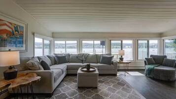 Una sala moderna con un sofá modular, una mesa de centro y vistas de la ciudad a través de amplios ventanales.
