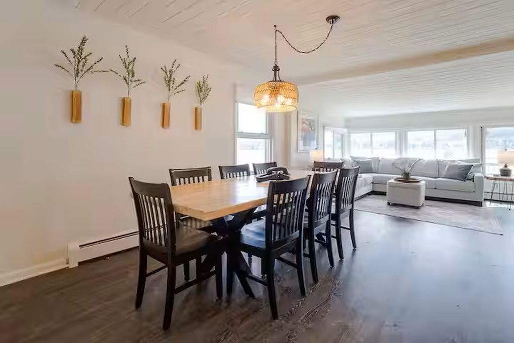 A dining area with a wooden table and chairs, a chandelier, and wall-mounted planters.