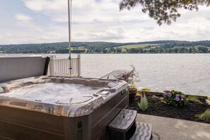 A hot tub with a view of a lake and hills.