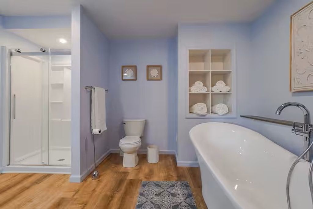 Un baño con ducha, inodoro, bañera y un estante con toallas.