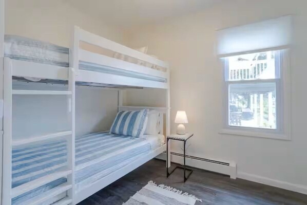 A room with bunk beds, a small table with a lamp, and a window with a view.