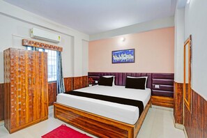 A bedroom with a bed, a wardrobe, a painting, and a window with curtains. - Classic The Suncity Hotel (Patna)