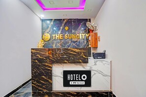 Hotellin vastaanottotiski, jossa on marmorikuviointi ja kyltti, jossa lukee: ”HOTEL OYO – palveluvalmis”.