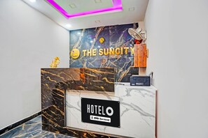 A hotel reception desk with a marble counter, a sign for 'THE SUNCITY HOTEL,' and a 'HOTEL OYO-Serviced' sign. - Classic The Suncity Hotel (Patna)