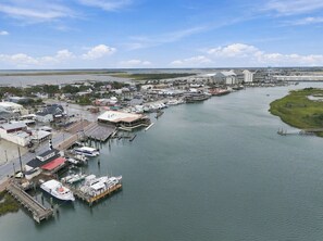 Ein Yachthafen mit vertäuten Booten, eine Stadt am Wasser und eine weite Wasserfläche.