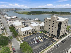 Un hôtel à plusieurs étages, avec un parking et une marina en arrière-plan.