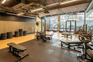 A gym with various exercise equipment, a wooden wall, and large windows. - Wembley Park 1 Bed | Sleep 4 | Gym, Workspace (Greater London)