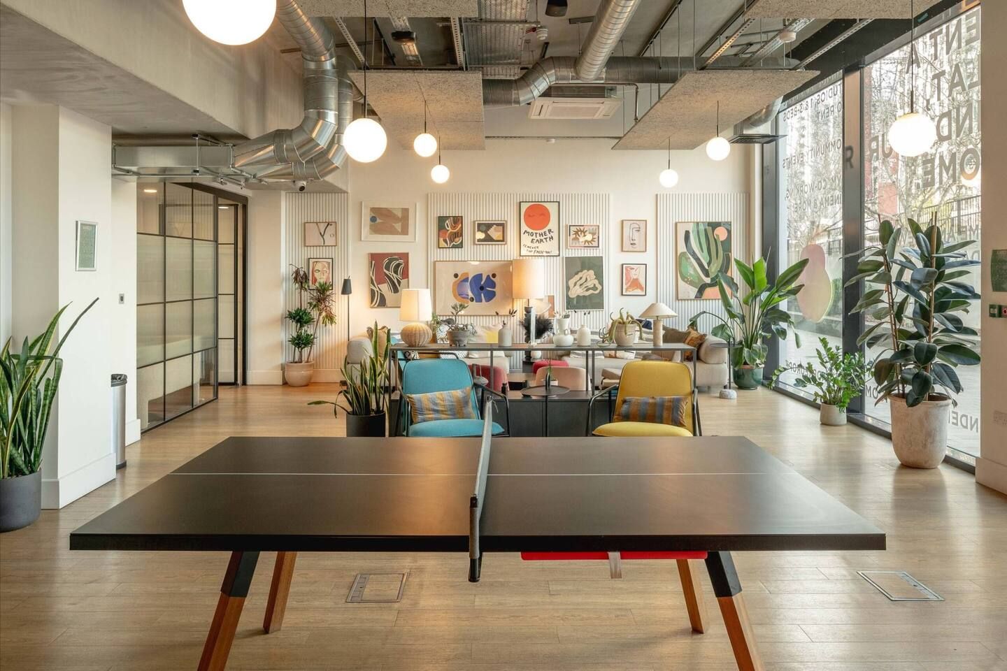 A modern interior with a ping pong table, seating area, and artwork on the walls.