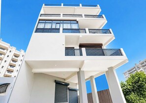 Um edifício com várias andares, varandas, janelas amplas e um céu claro.