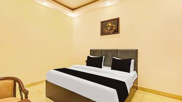 A hotel room with a bed, a chair, and a framed picture on the wall.