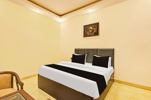 A hotel room with a bed, a chair, and a framed picture on the wall.
