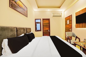 A hotel room with a large bed, a wooden door, a small table, and a chair.
