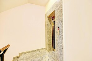 Escada com acabamento em granito que dá acesso a um elevador.