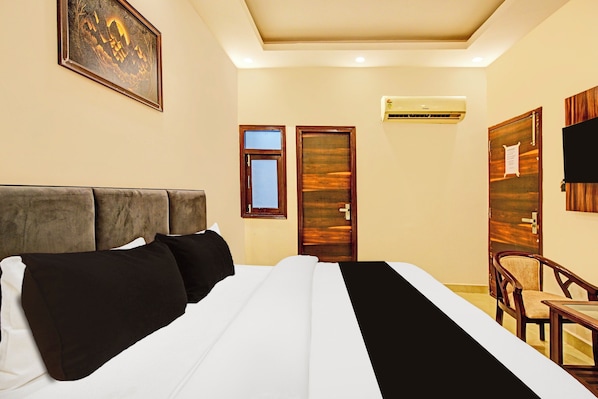 Una habitación de hotel con cama, una silla, una puerta y un equipo de aire acondicionado.