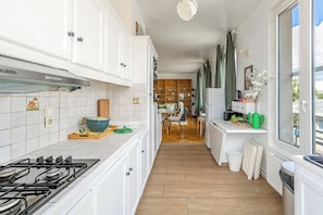 Eine moderne Küche mit weißen Schränken, einem Gasherd und Holzboden.