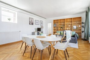 Ein modernes Wohnzimmer mit Essbereich, Bücherregal und einer Couch.