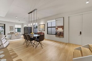 A modern living space with a dining area, a kitchen visible through a large window, and a cozy seating area. - Luxurious beautifully renovated Coconut Grove retreat with private Hot tub. (Miami)