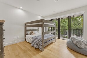 Une chambre avec un lit superposé, un canapé et un balcon donnant sur la forêt.