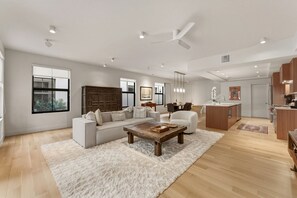 Un salon spacieux avec un grand canapé, une table basse et un tapis blanc.