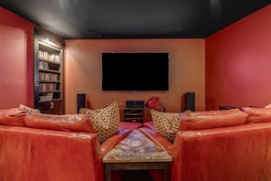 A living room with a flat-screen TV mounted on the wall, leather sofas, a coffee table, and a bookshelf. - Asheville Mountain Lodge by Biltmore; Creek, Hot Tub, Theater & Games (Asheville)