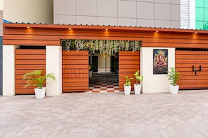 Fachada de edificio con diseño de paneles de madera, piso con estampado de cuadros y plantas en macetas.