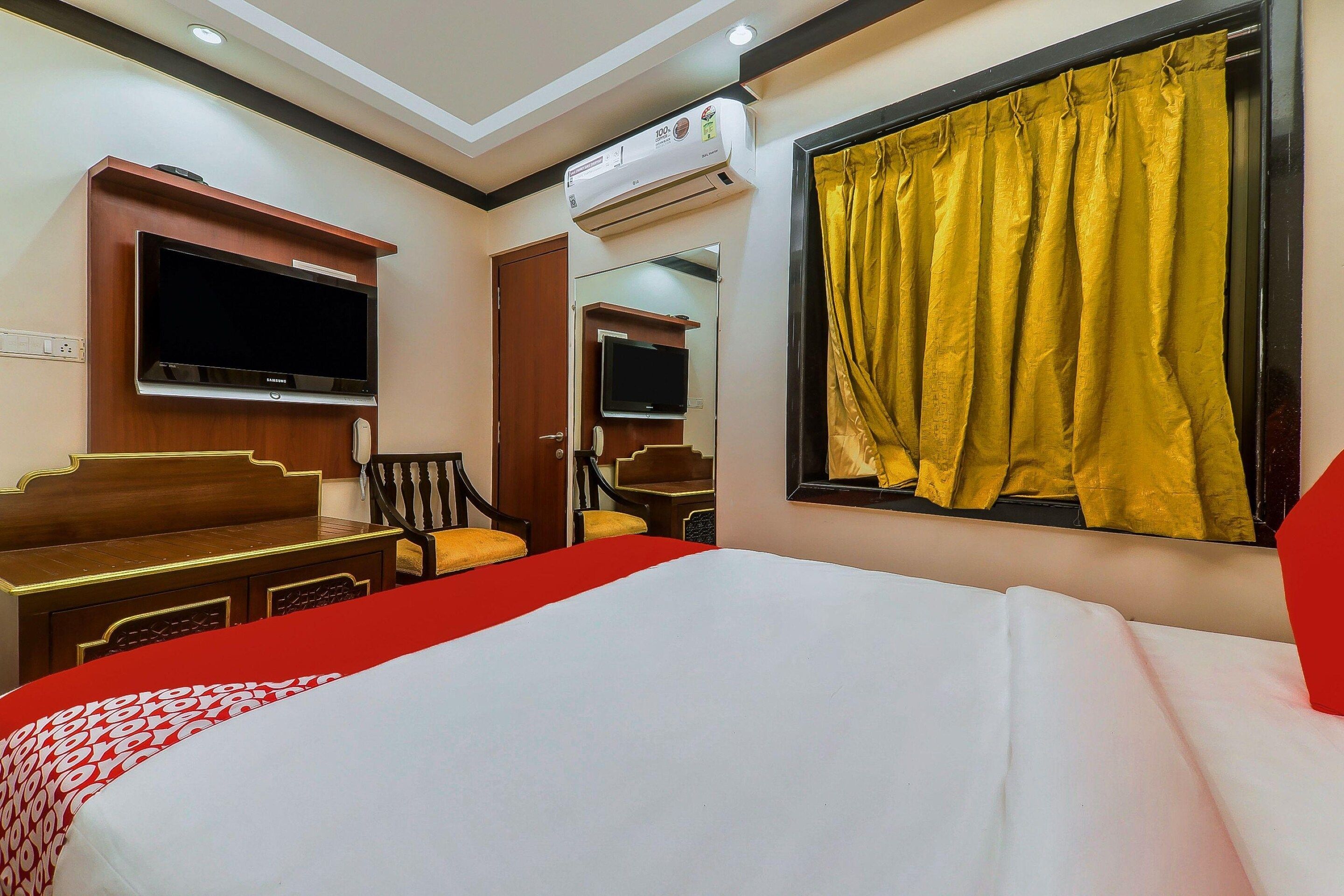 A hotel room with a bed, a TV, a desk, and a chair.