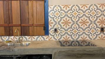 Cozinha com armário de madeira, pia e azulejos estampados.