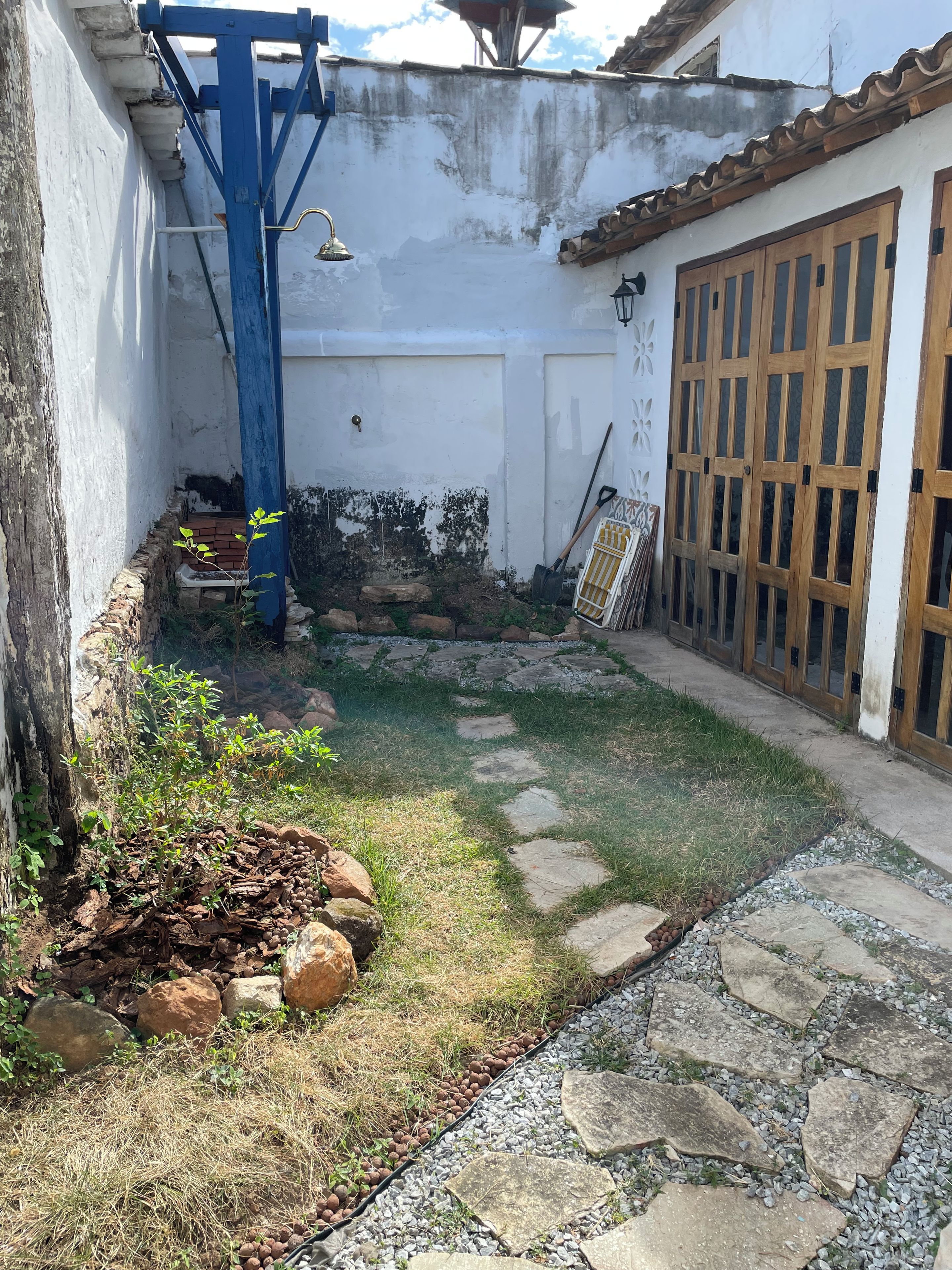 A courtyard with a stone pathway, a small garden area with plants, and a blue metal structure.