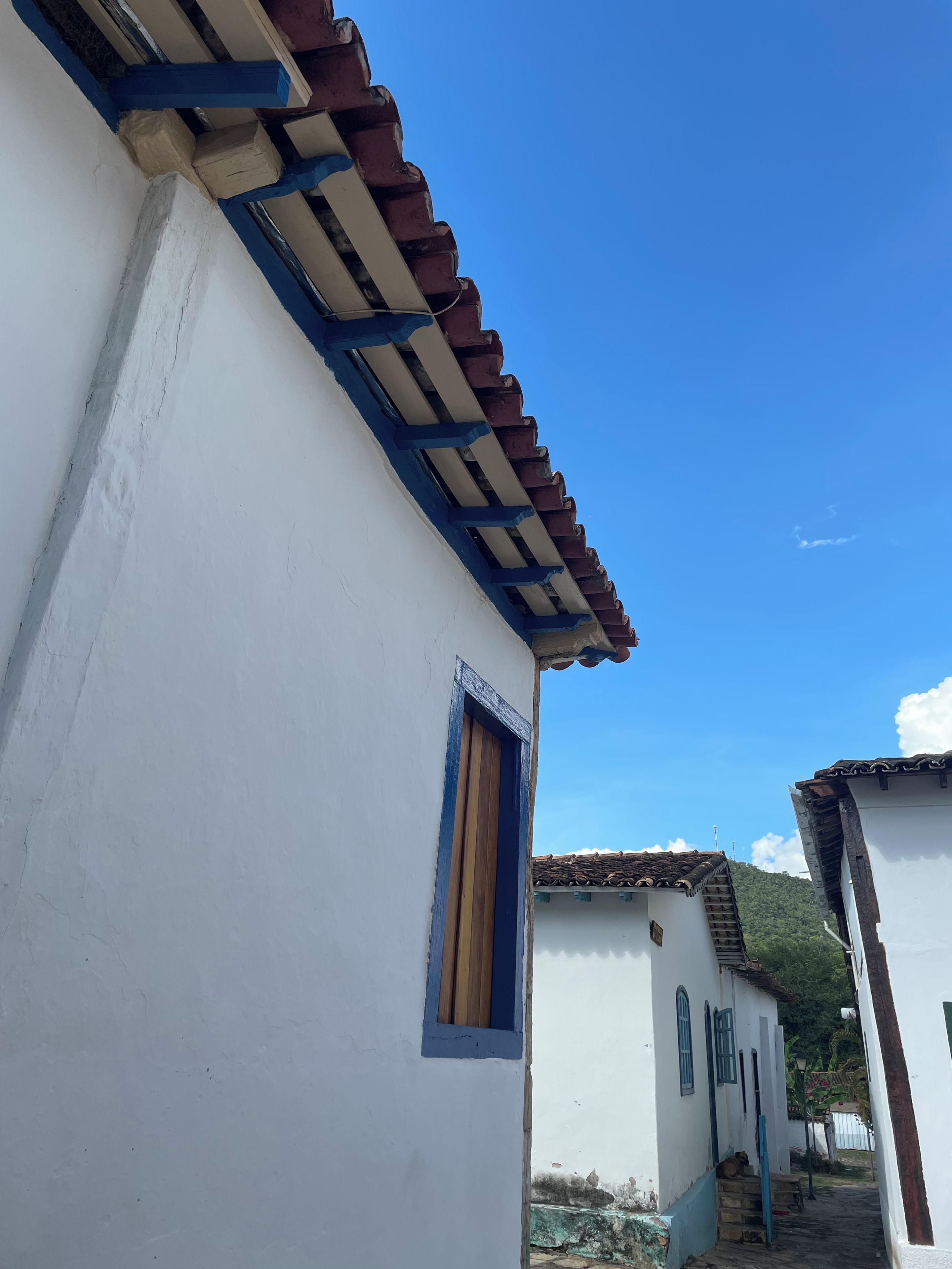 Un edificio blanco con un ventanal azul y techo de tejas.