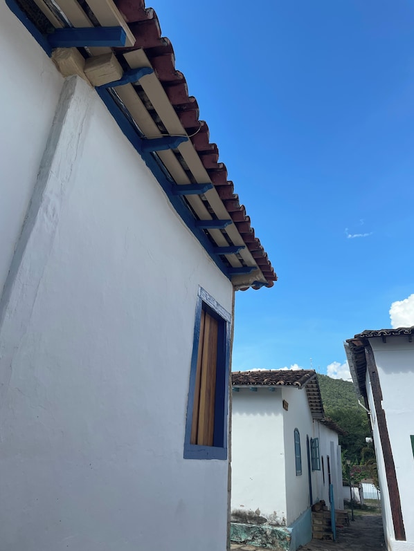 A white building with a blue window and a tiled roof.