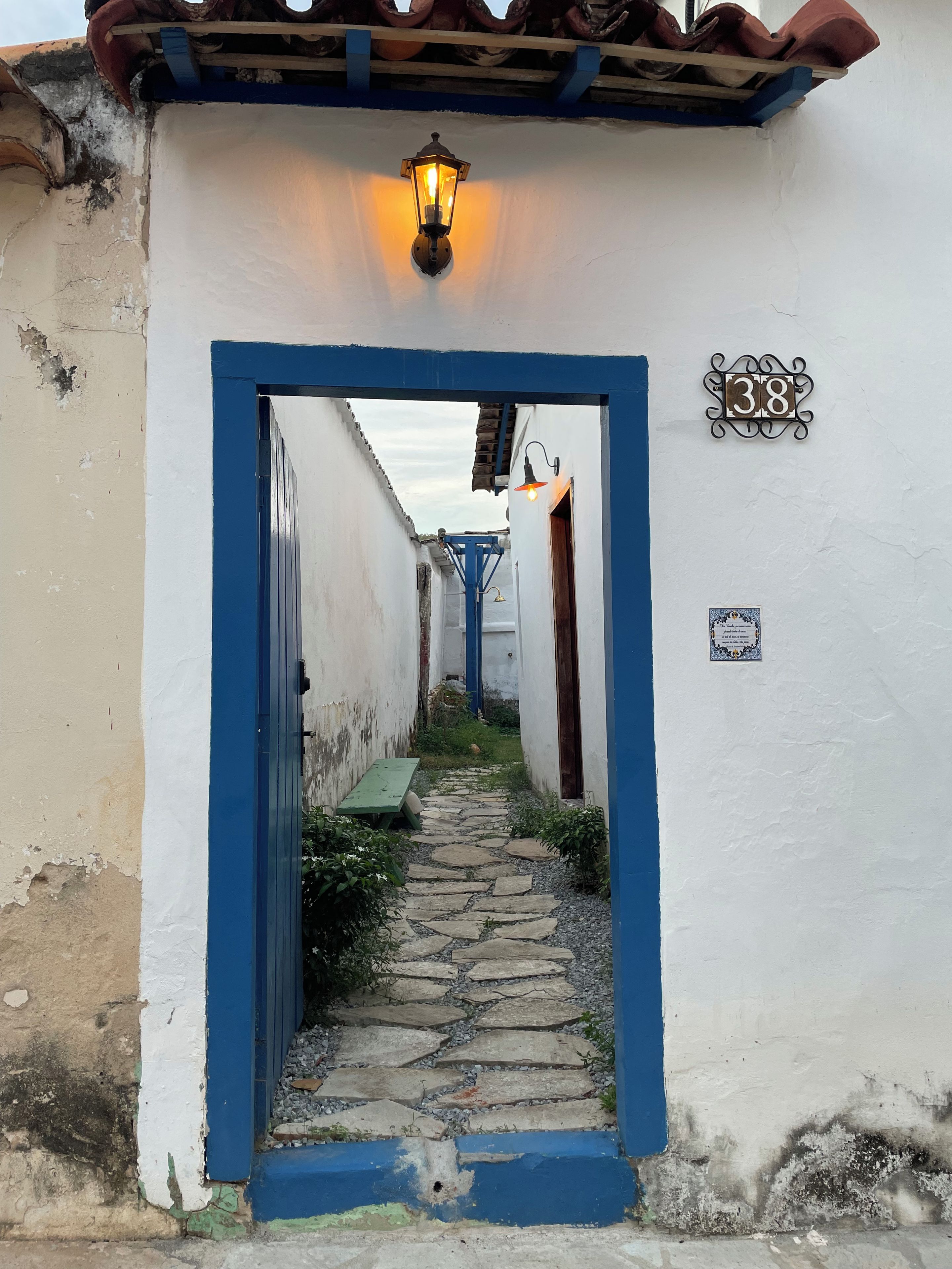 Une ruelle étroite avec un cadre de porte bleu, un chemin pavé et un numéro, « 38 », peint sur le mur.