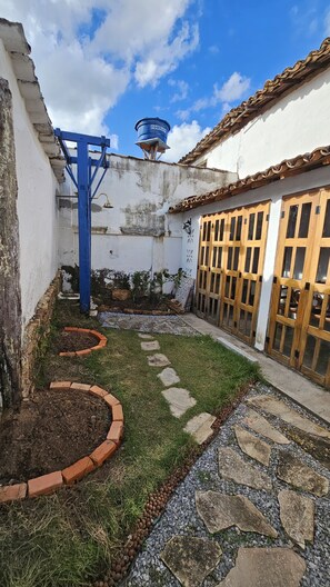 Un patio con un depósito de agua, un portón de madera y un sendero de piedra.