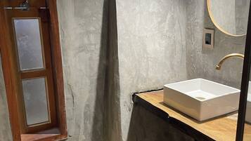 A bathroom with a wooden vanity, a white sink, a mirror, and a window with frosted glass.
