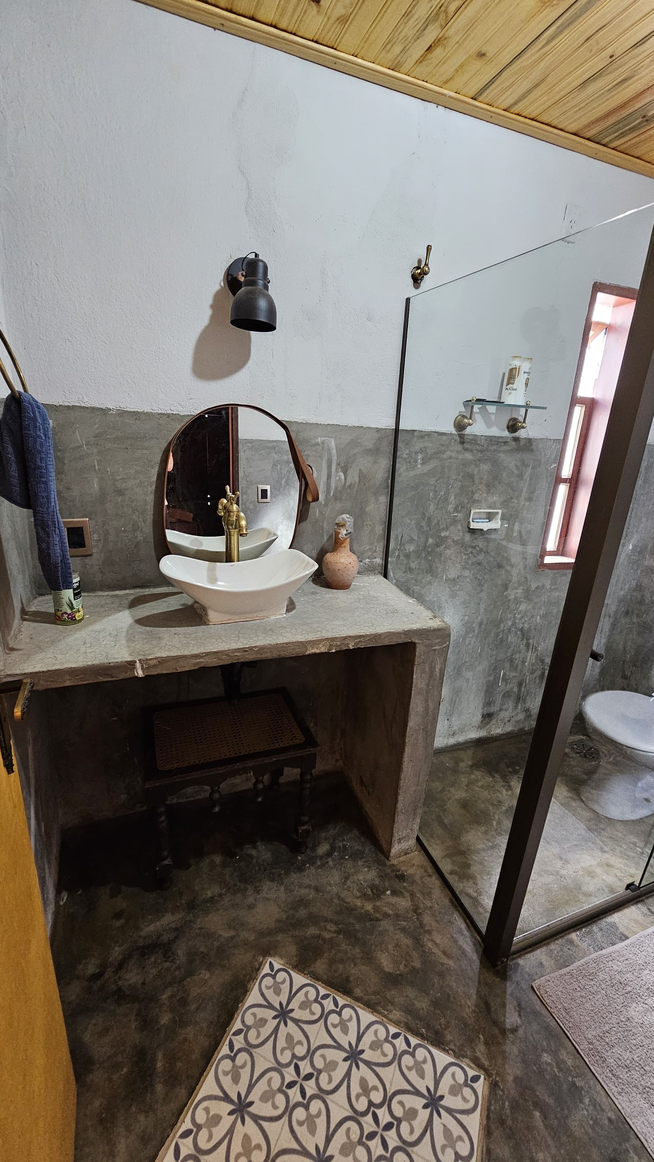 Um banheiro com pia, espelho e porta-toalhas.