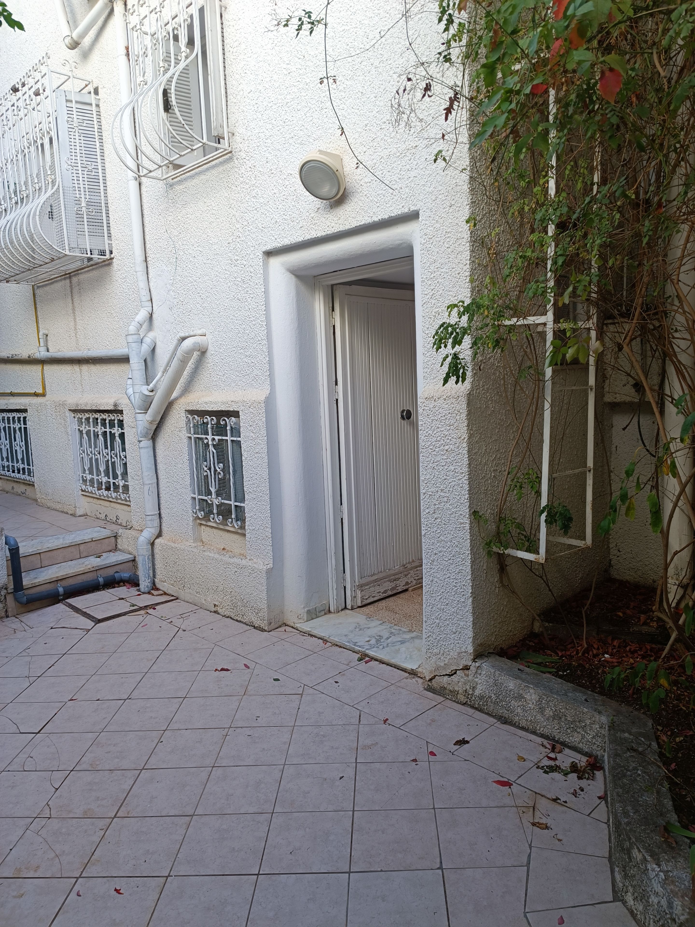 A building with a closed door, a window with metal bars, and a white exterior wall.