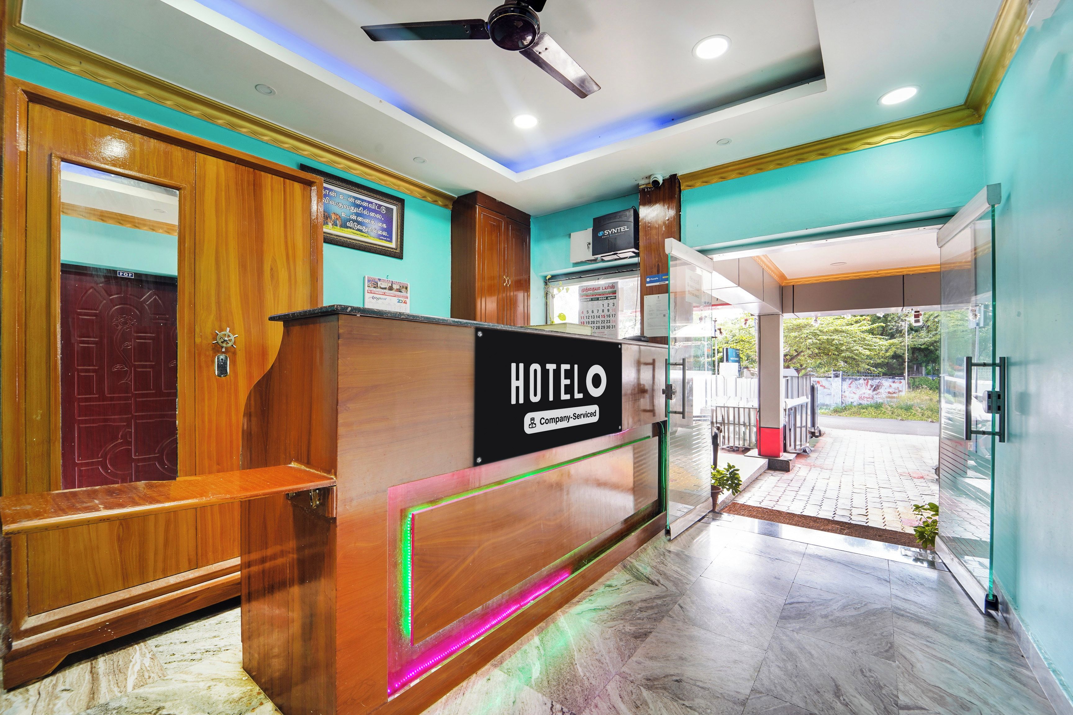 A hotel reception desk with a sign reading 'HOTELO Company Serviced'.