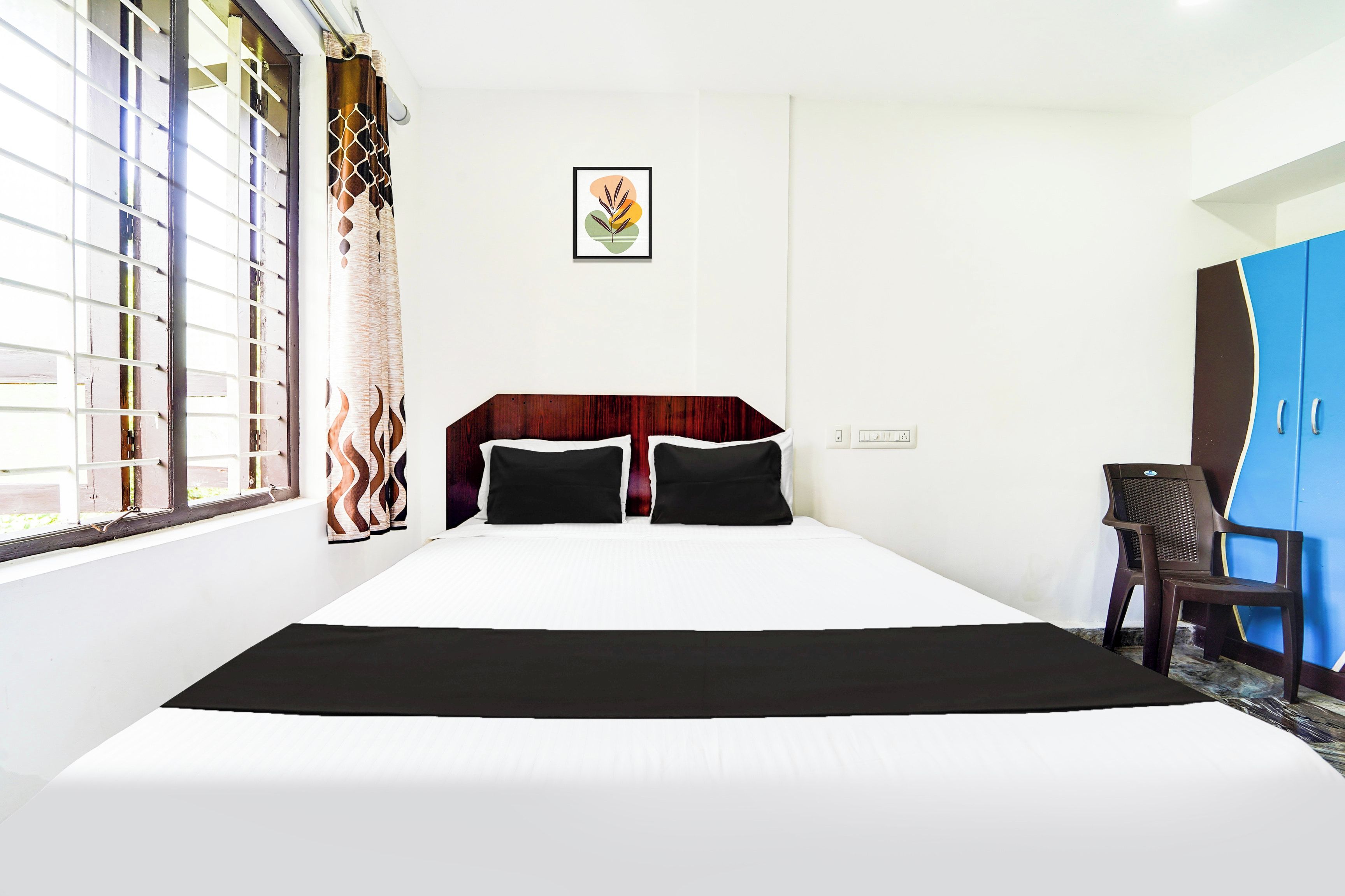 A hotel room with a large bed, a desk, and a wardrobe.