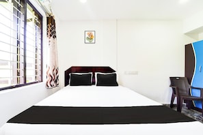 A hotel room with a large bed, a desk, and a wardrobe. - Hotel O Kanyakumari Near Sunrise View (Nagercoil)