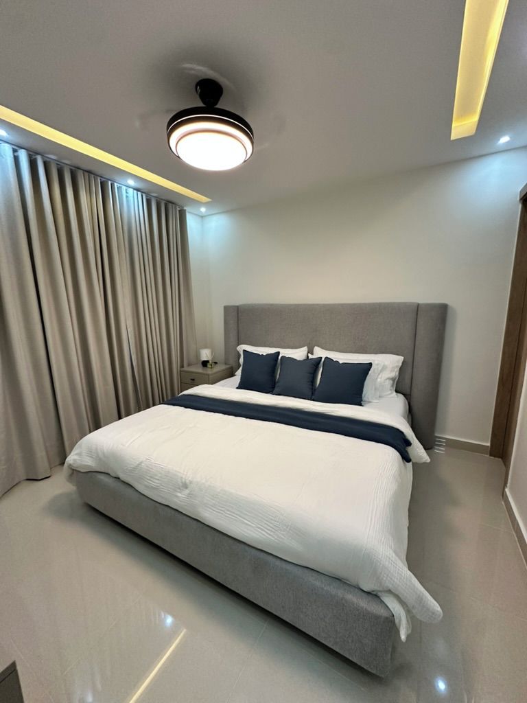 Ein modernes Hotelzimmer mit einem großen Bett, einem Nachttisch und einer Deckenleuchte.