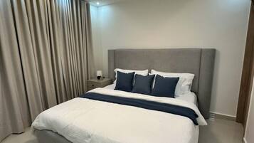 Ein modernes Hotelzimmer mit einem großen Bett, einem Nachttisch und einer Deckenleuchte.