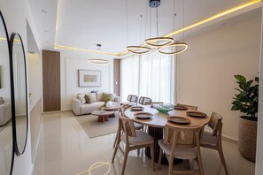 A modern dining area with a round table, wooden chairs, and a central light fixture.