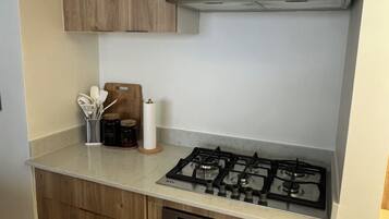 Eine kleine Küche mit Holzausstattung, einem Gasherd und einem Backofen.