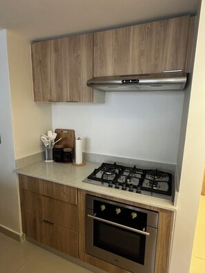 Eine kleine Küche mit Holzausstattung, einem Gasherd und einem Backofen.